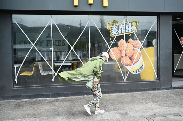 A woman walks past a closed fast food outlet with windows taped up for protection on Lantau island in Hong Kong on September 1, 2023, hours before the expected arrival of Super Typhoon Saola. Hong Kong grounded flights, shut down its stock market and closed schools on September 1 as Super Typhoon Saola barrelled towards China's southern coast. (Photo by Peter Parks/AFP Photo)