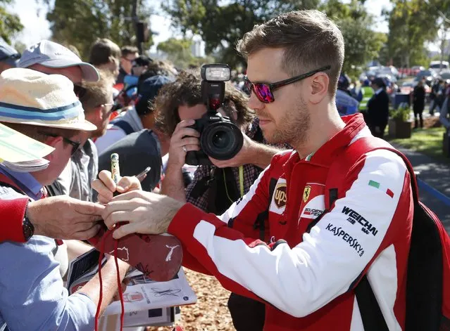 Ferrari Formula One driver Sebastian Vettel of Germany (R) signs autographs as he arrives for the first practice session of the Australian F1 Grand Prix at the Albert Park circuit in Melbourne March 13, 2015.    REUTERS/Brandon Malone