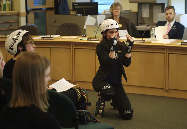 Heather “Hard Dash” Steeves wears a roller derby uniform as she makes a photo of another roller derby player testifying at a hearing by the The Committee on Labor, Commerce, Research and Economic Development Tuesday, February 2, 2016, at the State House in Augusta, Maine. She was one of the proponents at the hearing in support of a bill that legalizes the bumps and hits that accompany the sport. Roller derby advocates said the old statute prohibits skaters from hitting each other, so skaters have been forced to break the law for the last 10 years in Portland. (Photo by Tom Bell/AP Photo)