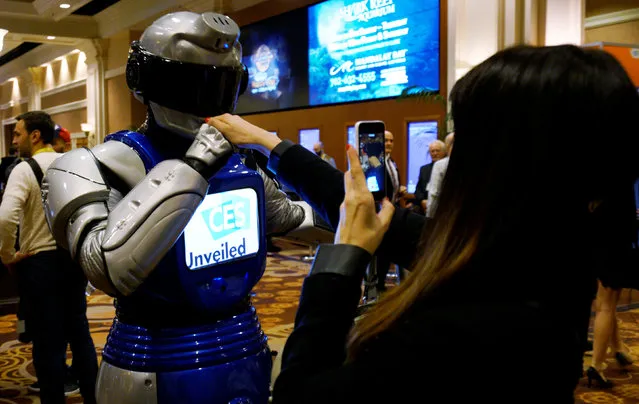 A man in a mechanized robotic costume kisses a woman's hand as she takes a picture of the encounter at the CES Unveiled event at CES in Las Vegas, January 3, 2017. (Photo by Rick Wilking/Reuters)