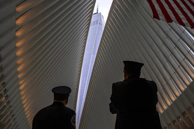 Two members of the New York City fire department look towards One World Trade Center through an opeining in the ceiling of the Oculus, part of the World Trade Center complex in New York, Tuesday, September 11, 2018, the anniversary of 9/11 terrorist attacks. The transit hall ceiling window was opened just before 10:28 a.m., marking the moment that the North Tower of the World Trade Center collapsed on September 11, 2001. (Photo by Craig Ruttle/AP Photo)