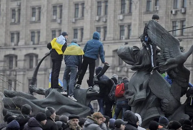 Protesters stands on a monument on Independent Square in Kiev, Ukraine, 01 December 2013. Tens of thousands of Ukrainians gathered in mass protests 01 December calling for the resignation of President Viktor Yanukovych over his decision to suspend a partnership and trade agreement with the European Union. (Photo by Filip Singer/EPA/EFE)