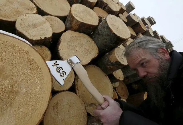Russian artist Vasily Slonov shows his artwork depicting an axe with symbols of world currencies which he called “Extraction money's axe”, on a bank of the Yenisei River in Krasnoyarsk, Siberia, Russia, February 20, 2016. Slonov showed his artwork specially for the Krasnoyarsk Economic Forum, according to him. (Photo by Ilya Naymushin/Reuters)