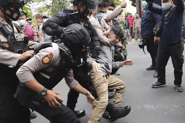Police officers scuffle with an Afghan refugee during a rally outside the building that houses UNHCR representative office in Jakarta, Indonesia, Tuesday, August 24, 2021. Hundreds of Afghan refugees living in Indonesia, mostly members of the Hazara ethnic minority, held the rally on Tuesday decrying the Taliban's takeover of their country and calling for resettlement in third countries. (Photo by Tatan Syuflana/AP Photo)