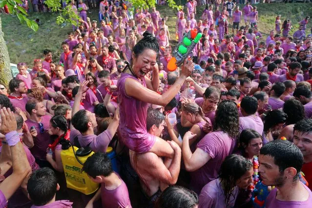 Covered in wine revellers enjoy during the “Batalla del Vino” (Battle of Wine) in Haro, on June 29, 2015. Every year thousands of locals and tourists climb a mountain in the northern Spanish province of La Rioja to celebrate St. Peter's day covering each other in red wine while tanker trucks filled with wine distribute the alcoholic beverage to water pistols, back mounted spraying devices, buckets which are randomly poured on heads and into any other available container. More than nine thousand people threw around 130,000 litres of wine during this year's Haro Wine Festival, according to local media. (Photo by Cesar Manso/AFP Photo)