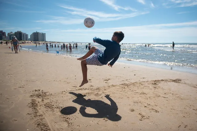 A boy plays soccer on the beach in Punta del Este, Uruguay, 03 February 2024. A seven-day heatwave, which began on 02 February, has hit Uruguay, bringing many people to the country's various beaches over the weekend. (Photo by Gianni Schiaffarino/EPA)