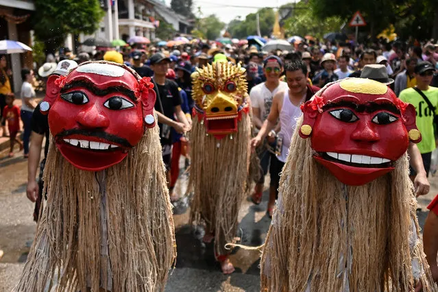 This photograph taken on April 15, 2019 shows men dressed as the legendary ancestors “Pou Nyer” and “Nyar Nyer” and their guardian lion “Singkheo Singkham” taking part in a procession to mark the Laos New Year or “Pi Mai” celebrations to the Wat Xiengthong Buddhist temple in Luang Prabang. Barefoot and cloaked in swinging bamboo ropes, Laos' legendary masked “ancestor” duo walk the streets of Luang Prabang for their annual outing for raucous new year celebrations that drew hundreds of worshippers to the normally sleepy city this year. (Photo by Manan Vatsyayana/AFP Photo)