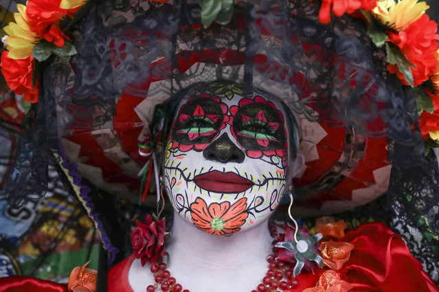 Carla Guzman is dressed as a Mexican skeletal iconic figure known as “La Catrina” ahead of the Day of the Dead celebrations, in Mexico City, Friday, October 29, 2021. In 1910, when Mexico was living under the exclusionary policies of dictator Porfirio Diaz, illustrator Jose Guadalupe Posada sketched the image of La Catrina as a tool for social satire. The implication was that the extravagance of a few who were accumulating vast wealth was killing others. Diaz was deposed at the start of the Mexican revolution, while the skeletal dame became etched in popular culture. (Photo by Emilio Espejel/AP Photo)