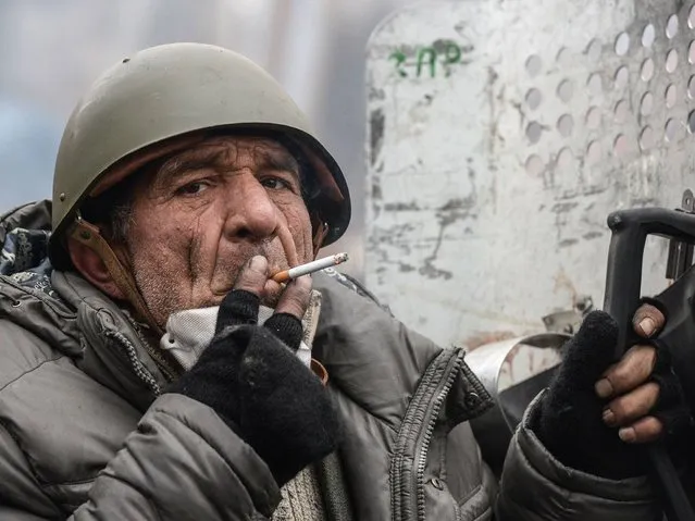 An elderly protester smokes during a break in clashes with police in central Kiev , on February 20, 2014. (Photo by Dmitry Serebryakov/AFP Photo)