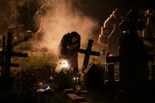 A woman burns incense near the grave of departed relatives in a cemetery 50 kilometers south west of Romanian capital Bucharest, in the early hours of Maundy Thursday, in Copaciu, Romania, April 25, 2019. (Photo by Octav Ganea/Inquam Photos via RReuters)