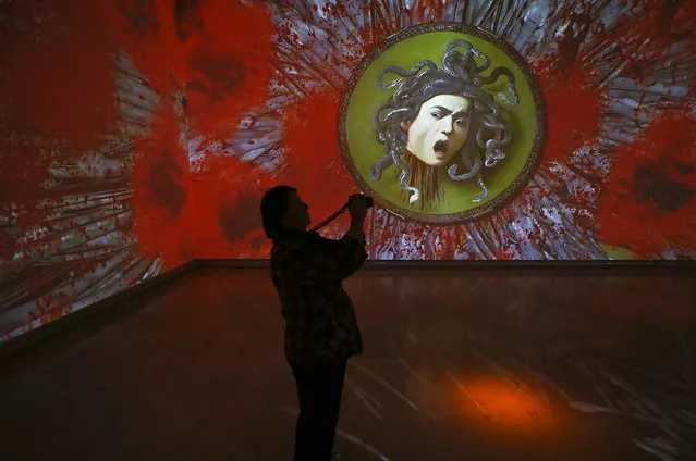 A visitor takes a picture of a video installation entitled “Caravaggio Experience” realized by video designer Stefano Fake and exhibited at the Palazzo delle Esposizioni in Rome, Italy March 31, 2016. (Photo by Tony Gentile/Reuters)