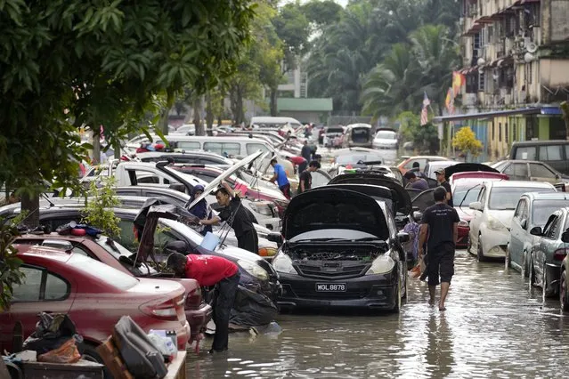 Residents check their car after water subsided outside their apartment in Shah Alam, on the outskirts of Kuala Lumpur, Malaysia, Monday, December 20, 2021. (Photo by Vincent Thian/AP Photo)