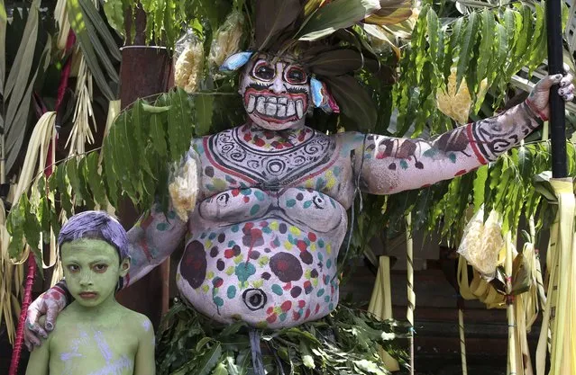 Gede Pasek and his son participate in the Hindu ritual Ngerebeg at Tegallalang village in Bali, Indonesia, April 3, 2024. In this ritual, participants paint their bodies with colorful paint and parade around their village to ward off evil spirits and bring happiness to the village. (Photo by Firdia Lisnawati/AP Photo)