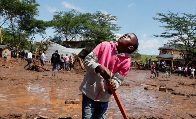 A boy looks at a helicopter hovering near the search and rescue location after heavy flash floods wiped out several homes when a dam burst, following heavy rains in Kamuchiri village of Mai Mahiu, Nakuru County, Kenya on April 29, 2024. (Photo by Thomas Mukoya/Reuters)