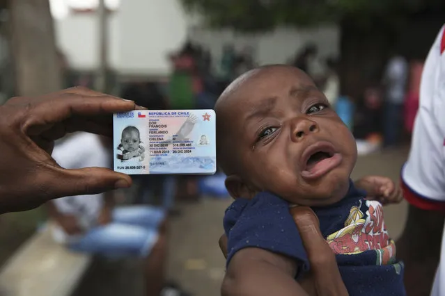 Chilean-born Haitian migrant Fernando Dor Francois, 5-months, cries as he's held next to his Chilean identification card at an immigration detention center where migrants had camped for weeks awaiting word on requests for asylum or permits that would allow them to continue north, in Tapachula, Mexico, Monday, June 3, 2019. President Donald Trump said he will impose a 5% tariff on Mexican goods on June 10 to pressure the Mexican government to block mostly Central American migrants from crossing into the U.S. (Photo by Marco Ugarte/AP Photo)
