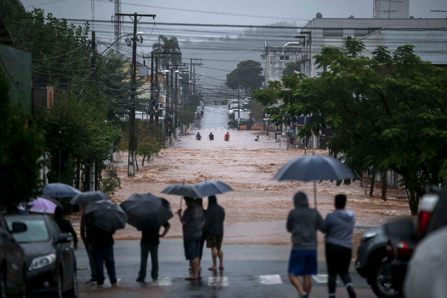 Residents observe a flooded street at the city center of Sao Sebastiao do Cai, Rio Grande do Sul state, Brazil on May 2, 2024. Brazilian President Luiz Inacio Lula da Silva on Thursday visited the country's south where floods and mudslides caused by torrential rains have killed 29 people, with the toll expected to rise. (Photo by Anselmo Cunha/AFP Photo)
