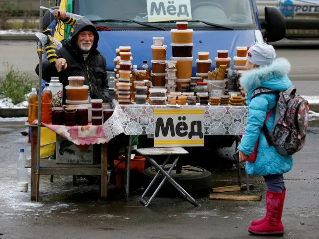Honey vendor talks to a girl at a street market in Krasnoyarsk, Russia, October 17, 2016. (Photo by Ilya Naymushin/Reuters)