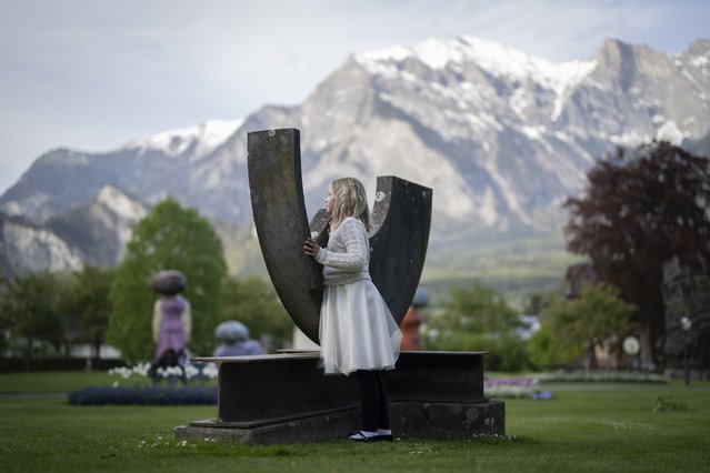 A girl stands next to the sculpture “T” by Swiss artist Al Meier at the international outdoor art exhibition “Bad Ragartz” in Bad Ragaz, Switzerland, 28 April 2024. (Photo by Gian Ehrenzeller/EPA/EFE)