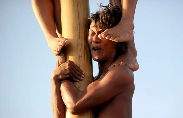 Participants climb greasy poles to claim a prize at Seminyak beach on the resort island of Bali on August 17, 2019, during a pole climbing contest to celebrate Indonesia's 74th anniversary of independence from Dutch rule. (Photo by Sonny Tumbelaka/AFP Photo)