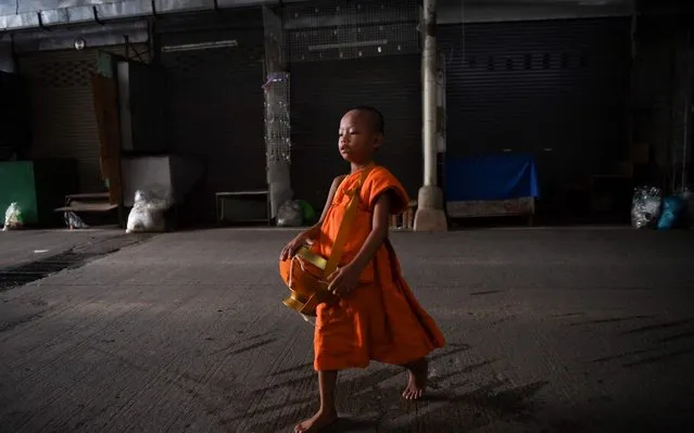 A novice Buddhist monk collects alms in a marketplace in Mae Sai, bordering Thailand and Myanmar, on June 14, 2019. (Photo by Lillian Suwanrumpha/AFP Photo)