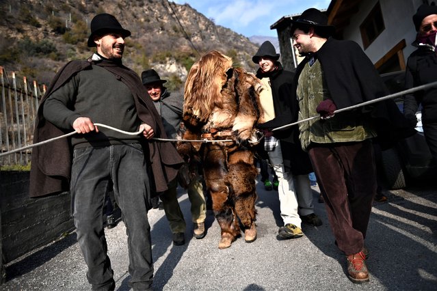 Man dressed as a bear is caught by participants during the annual “Fora l'Ours!” Festival on February 5, 2023 in Turin, Italy. The popular festival “Fora l'Ours” is a popular story from Mompantero where the legend states that a barbarian who arrived on the slopes of Rocciamelone, terrorizing the population, was a person who did not speak the local language and was completely covered in hair. Once captured he was tamed with red wine, and thanks to dancing with the most beautiful girl in the country, became integrated with the local population. (Photo by Stefano Guidi/Getty Images)