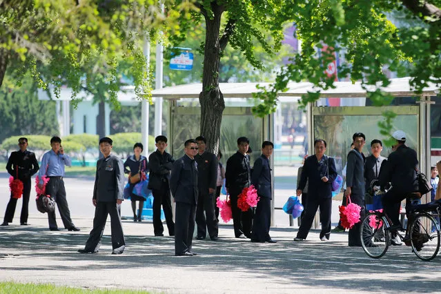 People, some carrying props for an apparent parade to celebrate the Workers' Party of Korea (WPK) congress, wait at a bus station in central Pyongyang, North Korea May 8, 2016. (Photo by Damir Sagolj/Reuters)