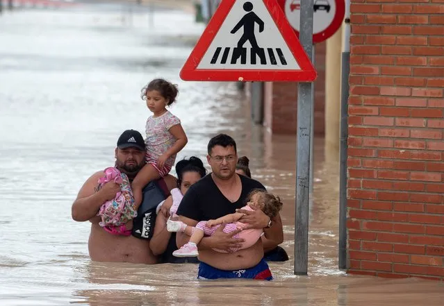 Peolple carry children on a flooded street in Almoradi on September 13, 2019. Two more people died as torrential rain and flash floods battered southeastern Spain, raising the death toll to four as the storm caused havoc for travellers and forced 3,500 people from their homes. (Photo by Jose Jordan/AFP Photo)
