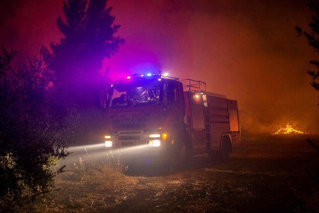 A fire truck is pictured in a forest on the slopes of the Throodos mountain chain, as a giant fire rages on the Mediterranean island of Cyprus, during the night of July 3, 2021. A huge forest blaze in Cyprus has killed four people, destroyed homes and forced evacuations of villages as Greece and other countries deployed fire-fighting planes to the Mediterranean island The fire began yesterday afternoon and has swept through districts in the southern foothills of the Troodos mountains as the country grapples with a blistering heatwave (Photo by AFP Photo/Stringer)