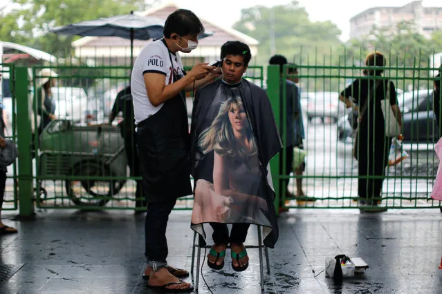 A man has a haircut on the street in Bangkok, Thailand October 16, 2016. (Photo by Jorge Silva/Reuters)