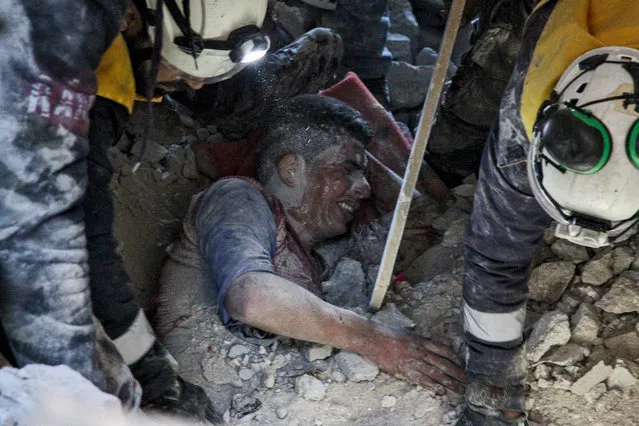 Members of the Syrian Civil Defence, also known as the White Helmets, rescue a survivor from the rubble of a collapsed building following a reported air strike in the village of Balyun in Syria's northwestern Idlib province on December 7, 2019. Syrian regime and Russian air strikes on December 7 killed over a dozen civilians, including children, in the country's last major opposition bastion of Idlib, the Syrian Observatory for Human Rights said. (Photo by Abdulaziz Ketaz/AFP Photo)