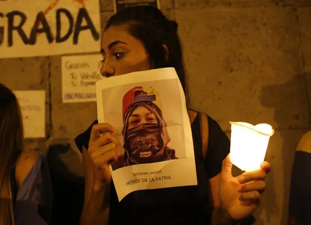 A woman holds a picture of Neomar Lander that reads in Spanish “Hero of the homeland” during a candlelight vigil at the site where he died in Caracas, Venezuela, Thursday, June 8, 2017. (Photo by Ariana Cubillos/AP Photo)