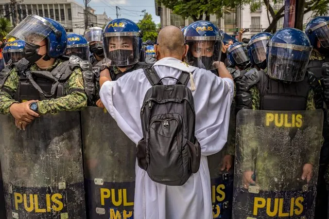A Catholic priest talks to police officers standing guard, as Filipinos take part in a protest against election results outside the Commission on Elections building on May 10, 2022 in Manila, Philippines. Ferdinand “Bongbong” Marcos Jr. is poised to win the presidency in a hotly contested election marred by several incidents of violence and numerous complaints of faulty vote counting machines. Marcos, the son and namesake of ousted dictator Ferdinand Marcos Sr. who was accused and charged of amassing billions of dollars of ill-gotten wealth as well as committing tens of thousands of human rights abuses during his autocratic rule, mounted a hugely popular campaign based largely on disinformation to return his family name to power. Election results a day after millions of Filipinos went to polls show Marcos enjoying a massive lead against main rival Vice President Leni Robredo. Also poised to win the vice presidency is Mayor Sara Duterte of Davao City, the daughter of outgoing President Rodrigo Duterte who is the subject of an international investigation for alleged human rights violations during his war on drugs. (Photo by Ezra Acayan/Getty Images)