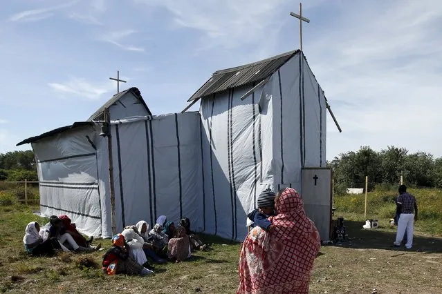Christian migrants from Eritrea and Ethiopia attend the Sunday mass at the makeshift church in “The New Jungle” near Calais, France, August 2, 2015. Some 3,000 migrants live around the tunnel entrance in a makeshift camp known as “The Jungle”, making the northern French port one of the frontlines in Europe's wider migrant crisis. (Photo by Pascal Rossignol/Reuters)