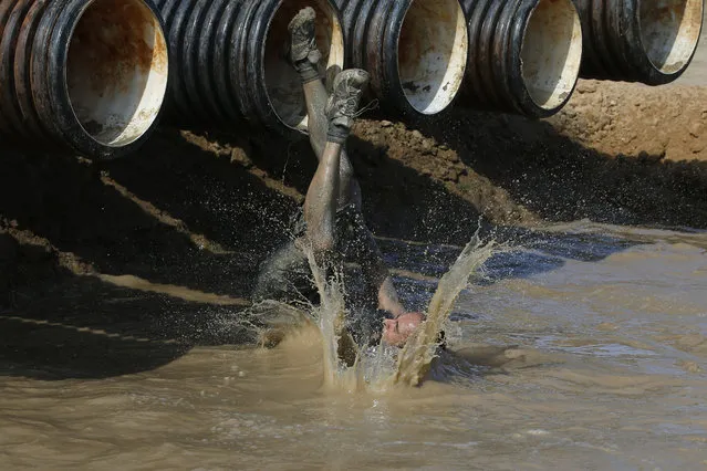 A participant dives into a mud pool during the Mud Day athletic event at El Goloso Military base on the outskirts of Madrid, Spain, Saturday, June 11, 2016. Thousands of athletes got covered in mud as they celebrated International Mud Day running a 13-kilometer obstacle course on a sunny Saturday with heatwave-like temperatures up to a 29 degrees Celcius (around 84 degrees Fahrenheit). (Photo by Paul White/AP Photo)