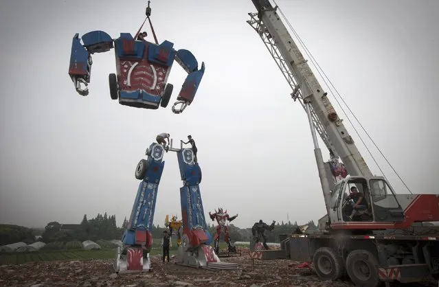 Workers assemble a 30-foot-tall homemade “Transformers” replica on the outskirts of Shanghai, on June 30, 2014. Li Lei, owner of a small factory, builds “Transformers” replicas for rent or sale. The new Transformers movie has brought the factory many new orders, according to Li. (Photo by Reuters/China Daily)