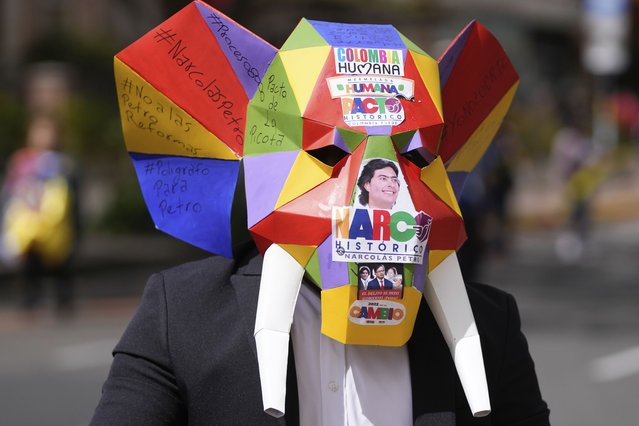 A protester wears a mask during a march against Colombian President Gustavo Petro's government, in Bogota, Colombia, Tuesday, June 20, 2023. Colombia's opposition is protesting sweeping reforms to the nation's healthcare system, pensions and labor. (Photo by Fernando Vergara/AP Photo)