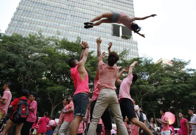 Participants dressed in pink perform cheerleading stunts before taking part in the forming of a giant pink dot at the Speakers' Corner in Hong Lim Park in Singapore June 28, 2014. The annual Pink Dot Sg event promotes an acceptance of the Lesbian, Gay, Bisexual and Transgender (LGBT) community in Singapore, according to organizers. (Photo by Edgar Su/Reuters)