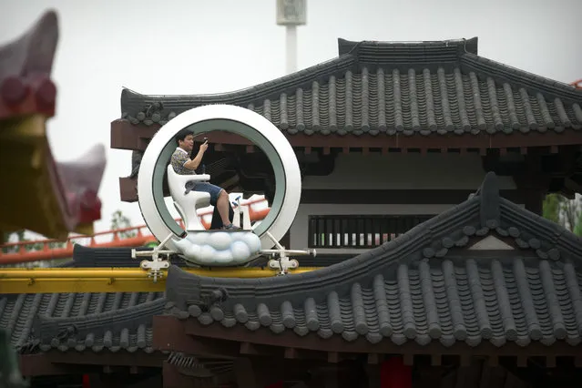 In this May 28, 2016, photo, people ride on an elevated attraction during the grand opening of the Nanchang Wanda Park theme park in Nanchang in southeastern China's Jiangxi province. Chinese conglomerate Wanda Group, owner of Hollywood's Legendary Studios, is selling most of its theme parks, retreating from a business it once said would challenge Walt Disney Co. (Photo by Mark Schiefelbein/AP Photo)