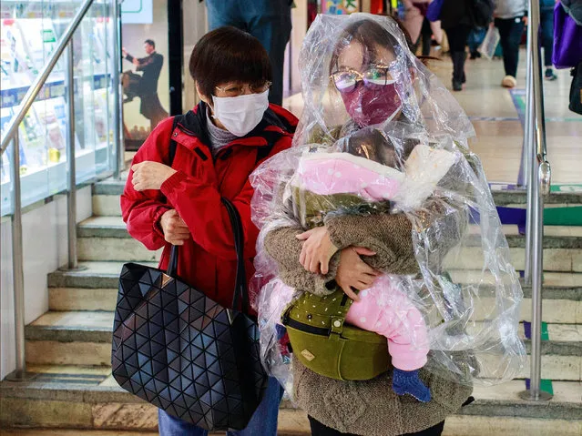 A woman with her child wrapped in a plastic sheet walks on a street in Hong Kong on January 29, 2020. (Photo by Kevin On Man Lee/Penta Press/Rex Features/Shutterstock)