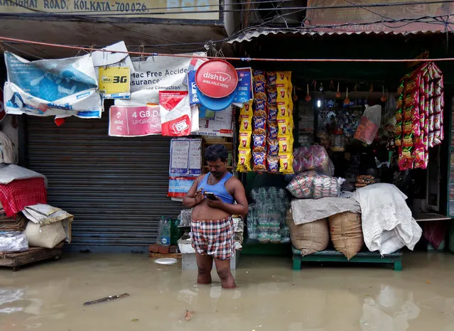 A man checks his mobile phone as he stands in a waterlogged street after rainfall in Kolkata, July 26, 2017. (Photo by Rupak De Chowdhuri/Reuters)