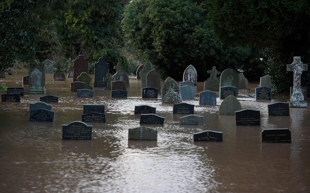 Flood water surrounds grave stones in a graveyard in Tenbury Wells, after the River Teme burst its banks in western England, on February 16, 2020, after Storm Dennis caused flooding across large swathes of Britain. A man died after falling into a river on Sunday as Storm Dennis swept across Britain with the army drafted in to help deal with heavy flooding and high winds. (Photo by Oli Scarff/AFP Photo)