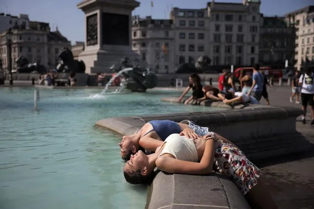Two women dip their heads into the fountain to cool off in Trafalgar Square on July 19, 2022 in London, United Kingdom. Temperatures were expected to hit 40C in parts of the UK this week, prompting the Met Office to issue its first red extreme heat warning in England, from London and the south-east up to York and Manchester. (Photo by Dan Kitwood/Getty Images)