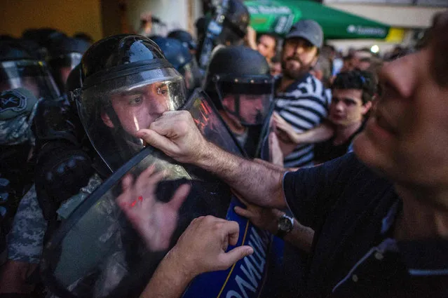 Riot police stands guard in front of protestors gesturing during an anti-government protest in Skopje on July 11, 2016. Macedonia has been locked in political crisis for more than a year, with anti-government protests fueled by allegations that the ruling conservatives had authorized wiretaps of opponents and thousands of senior officials. Political leaders have faced delays in implementing a European Union-brokered agreement to hold early elections. (Photo by Robert Atanasovski/AFP Photo)