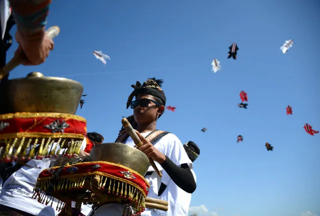 Balinese men perform traditional music during a kite festival in Denpasar on Indonesia's resort island of Bali on July 23, 2016. The Bali kite festival celebrates the most extravagant Indonesian kites throughout the island to promote tourism and runs from July 22 to 24. (Photo by Sonny Tumbelaka/AFP Photo)