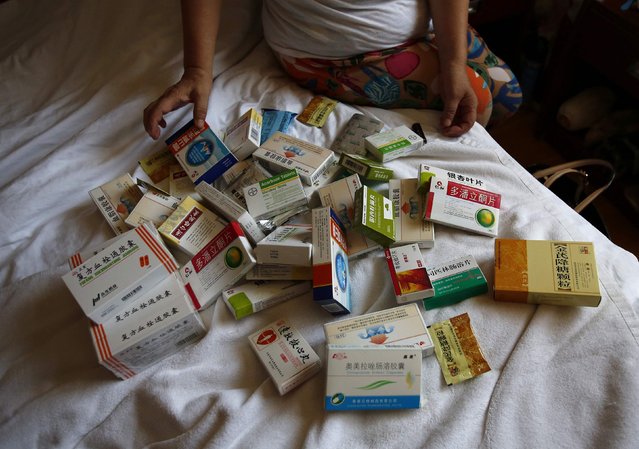 Li, whose son Wen Yongsheng was onboard Malaysia Airlines Flight MH370 which disappeared on March 8, 2014, shows medicine for herself and her husband which they take every day during an interview with Reuters in Beijing July 11, 2014. (Photo by Kim Kyung-Hoon/Reuters)
