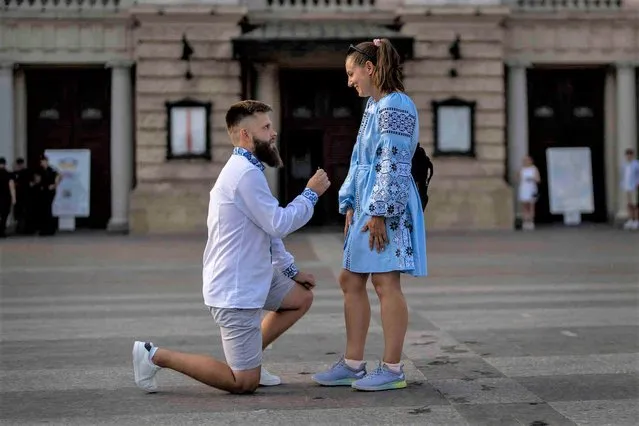 Oleksandr offers an engagement ring to his girlfriend Kateryna in downtown Lviv, Ukraine, Saturday, August 27, 2022. Kateryna, who just returned from Poland on Saturday, was met at the Lviv train station by her fiancé Oleksandr, ending six months of separation because of the war. (Photo by Evgeniy Maloletka/AP Photo)