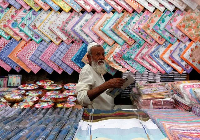 A vendor selling handkerchiefs reads a newspaper as he waits for customers at a market in Mumbai, India, July 25, 2016. (Photo by Shailesh Andrade/Reuters)