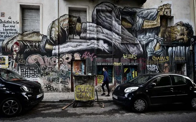 A woman walks past a work by a Bali-born graffiti artist WD (Wild Drawing) in central Athens on October 11, 2017. WD and Cacao Rocks, are taking part in an ongoing exhibition devoted to “Artists in Athens, City of Crisis”. 'Every wall of abandoned buildings is a canvas for us' says Cacao Rocks and explains how the Greek capital hit by the financial crisis and then that of the migrants, is transformed into an “international meeting point” of street art. (Photo by Louisa Gouliamaki/AFP Photo)