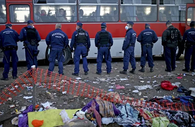 Hungarian policemen stand outside a bus with migrants at a collection point in Roszke, Hungary September 14, 2015. (Photo by Dado Ruvic/Reuters)