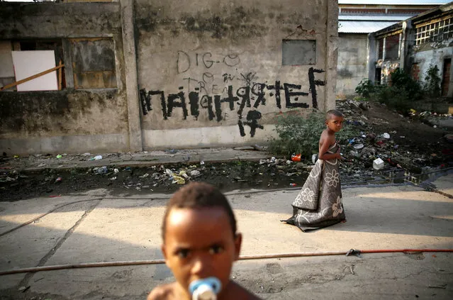 Kids walk and gather outside an occupied building in the Mangueira “favela” community on August 9, 2016 in Rio de Janeiro, Brazil. Hundreds of residents who live in the surrounding structures must collect water from hoses as there is no running water in the buildings. Residents often must burn trash due to a lack of public services. Much of the Mangueira “favela” community sits about a kilometer away from Maracana stadium, the site of the opening and closing ceremonies for the Rio 2016 Olympic Games. The stadium has received hundreds of millions of dollars in renovations ahead of the World Cup and Olympics. (Photo by Mario Tama/Getty Images,)